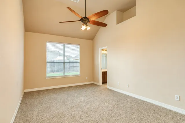 an empty room with a chandelier fan and windows