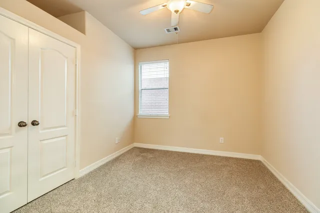 an empty room with windows and ceiling fan