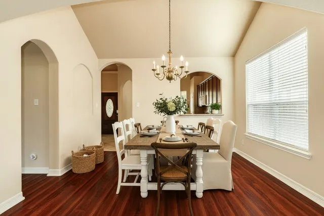 a dining room with chandelier fan and wooden floor