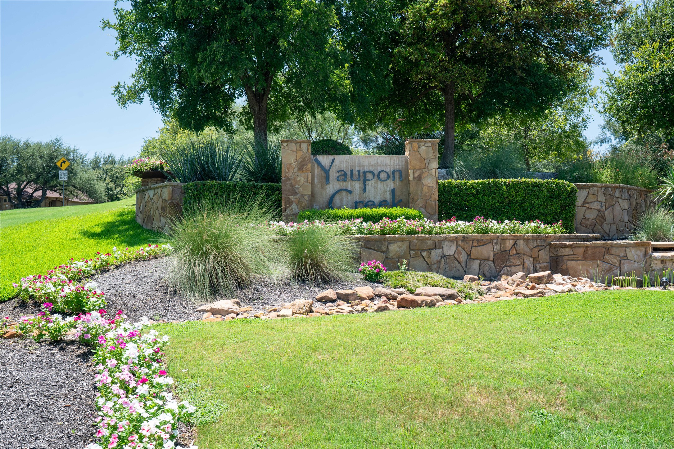 Discover the inviting stone and greenery entrance to this charming neighborhood.