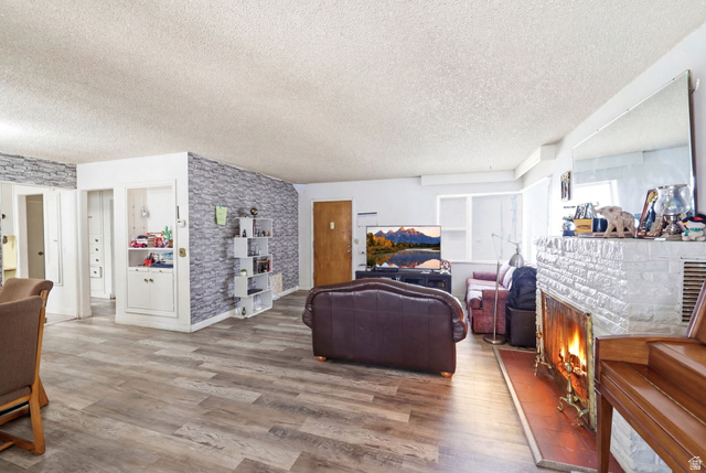 5480 South 2000th Street West Roy, UT 84067 - Photo 12 of 36 Spacious living area featuring wood-finish flooring, a white brick fireplace with a hearth, and a built-in display cabinet