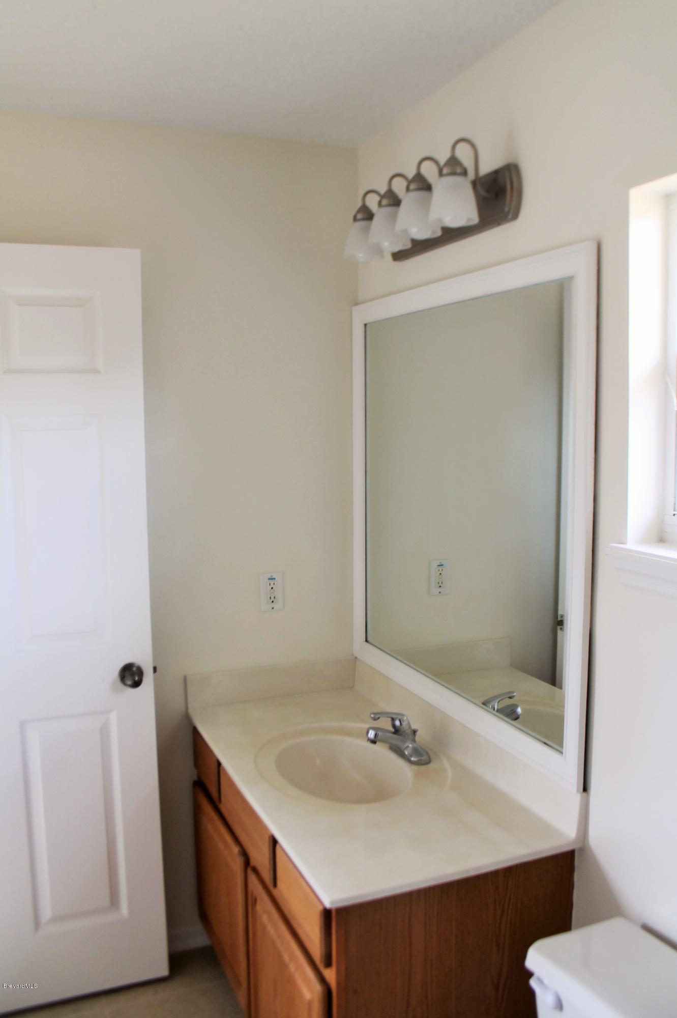 575 Amber Lane Cocoa, FL 32926 - Photo 10 of 16 a bathroom with a sink and mirror with toilet
