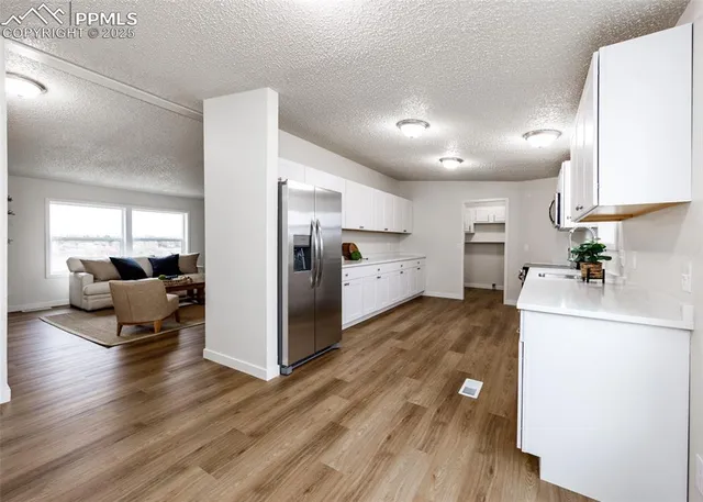 a kitchen with white cabinets and wooden floor