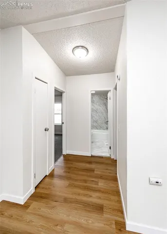 a view of an empty room with kitchen and a window