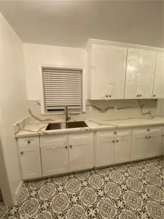 a room with granite countertop cabinets sink and a window