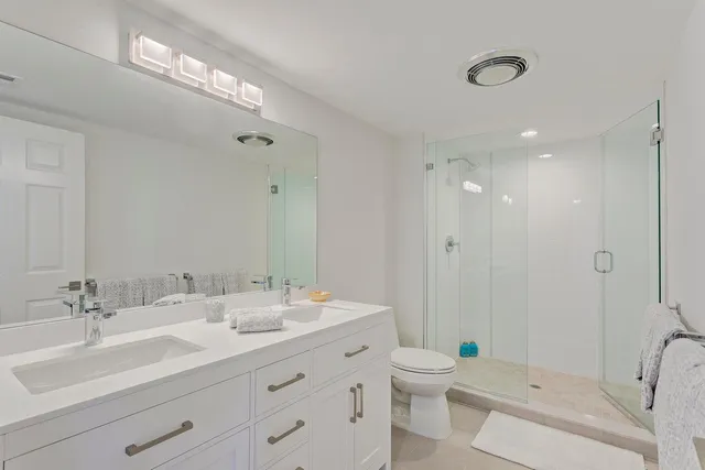 a bathroom with a double vanity sink toilet and shower