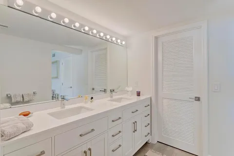 a spacious bathroom with double sink a mirror and shower