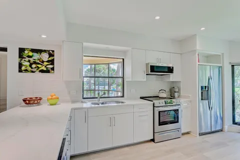 a utility room with stainless steel appliances white cabinets and wooden floors