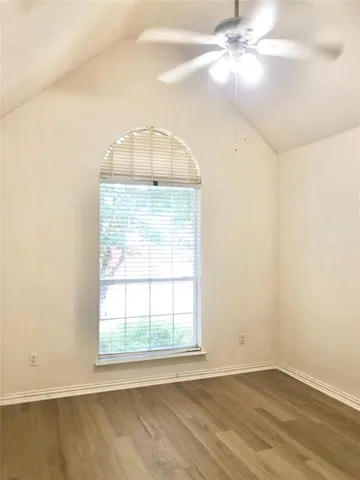 an empty room with a chandelier fan and windows