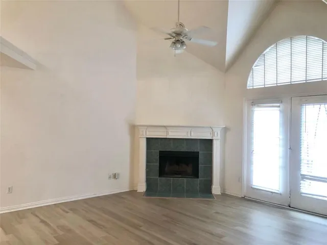an empty room with wooden floor fireplace and windows