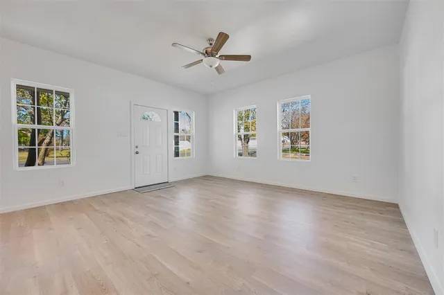 a view of an empty room with a window and wooden floor