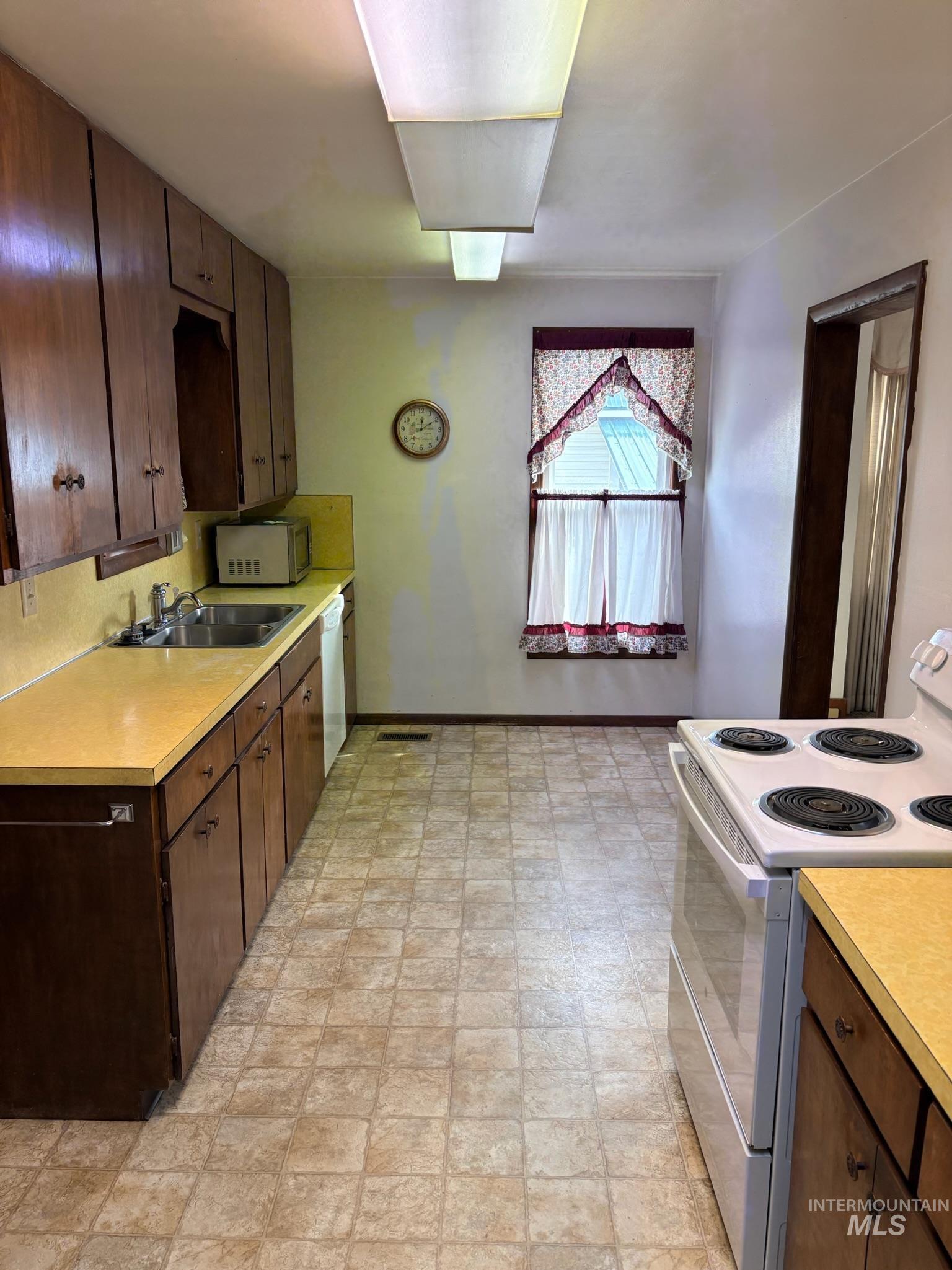 627 Southwest 3rd Street Fruitland, ID 83619 - Photo 12 of 35 Kitchen with white appliances, dark brown cabinetry, and light countertops
