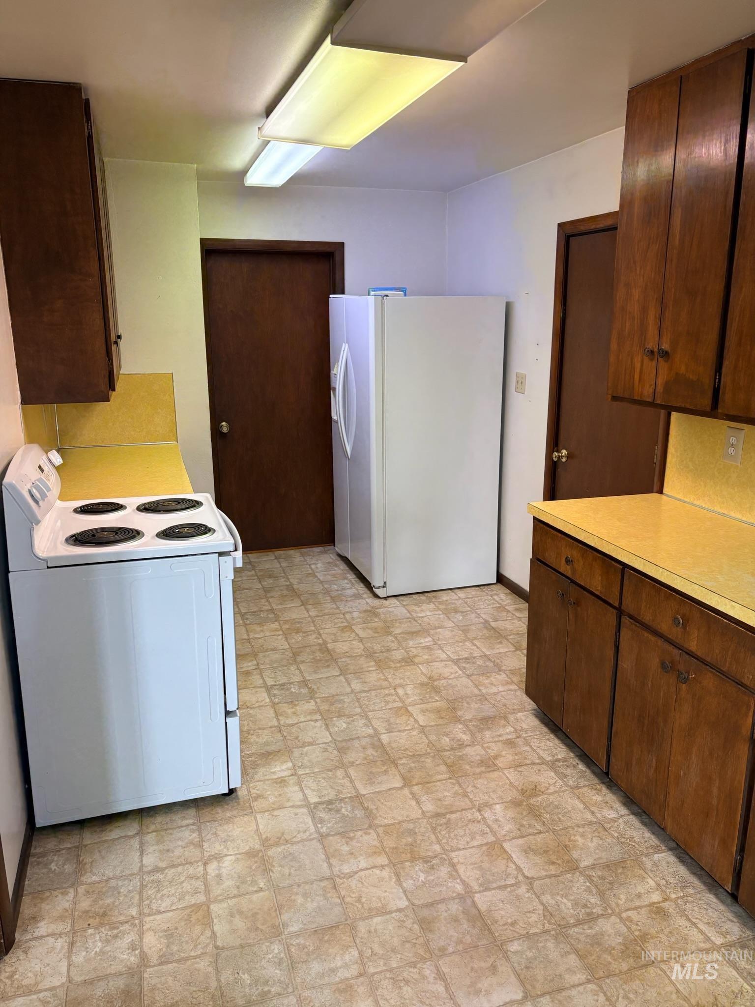 627 Southwest 3rd Street Fruitland, ID 83619 - Photo 15 of 35 Kitchen with white appliances, light countertops, and dark brown cabinets