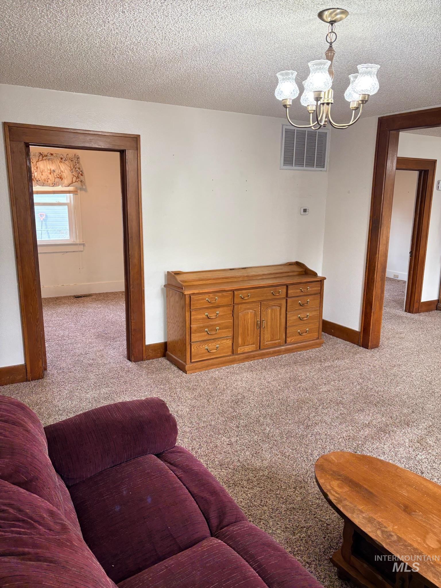 627 Southwest 3rd Street Fruitland, ID 83619 - Photo 7 of 35 Living room featuring a textured ceiling, light colored carpet, and a chandelier