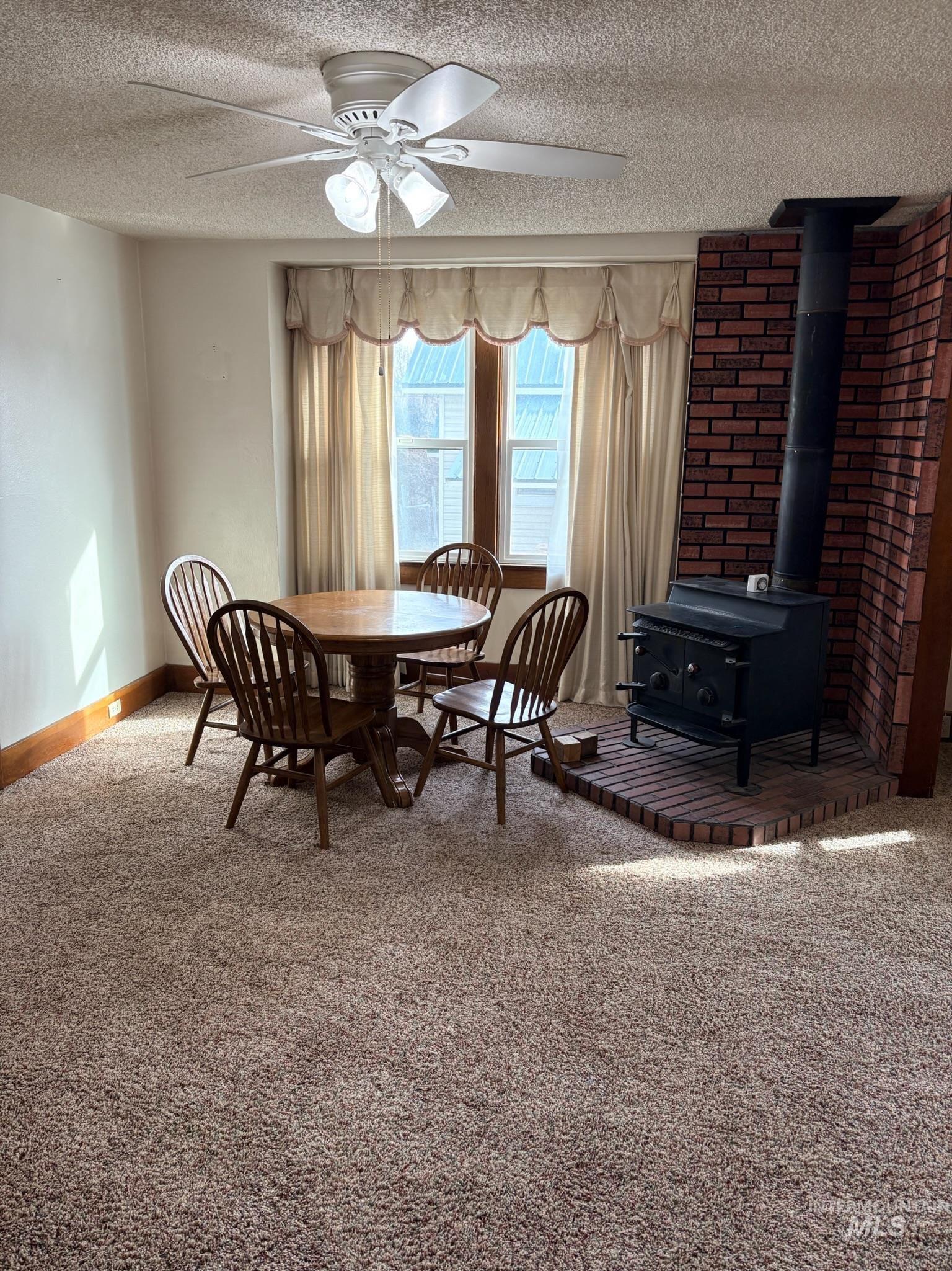 627 Southwest 3rd Street Fruitland, ID 83619 - Photo 10 of 35 Dining space with a wood stove, carpet, ceiling fan, and a textured ceiling