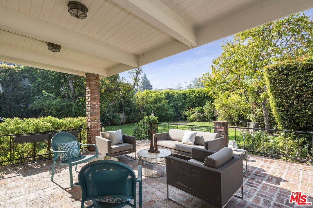 513 Foothill Road Beverly Hills, CA 90210 - Photo 6 of 9 a view of a patio with couches chairs potted plants and a palm tree