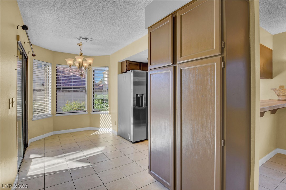 6440 Hartwood Road Las Vegas, NV 89108 - Photo 13 of 59 A well-lit eat-in kitchen area with bay windows and tiled flooring.
