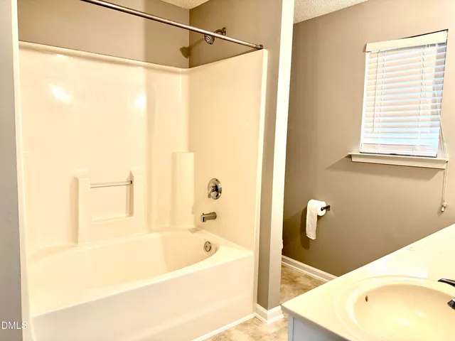 a bath tub sitting next to a white sink and a shower