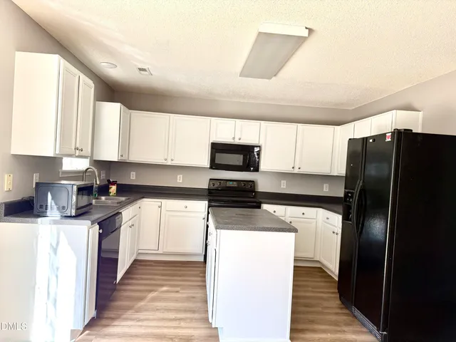 a kitchen with stainless steel appliances granite countertop a refrigerator a stove and a sink