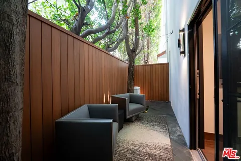 a backyard of a house with couches plants and wooden fence