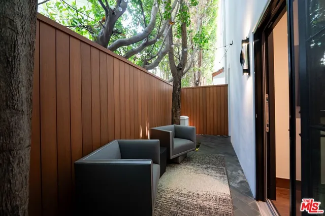 a backyard of a house with couches plants and wooden fence