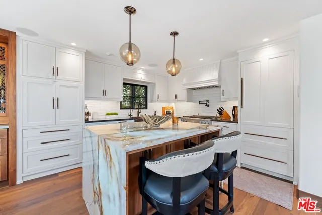 a kitchen with stainless steel appliances granite countertop a table chairs and a refrigerator
