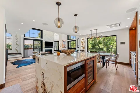 a large kitchen with stainless steel appliances granite countertop a stove a sink dishwasher and a fireplace with wooden floor