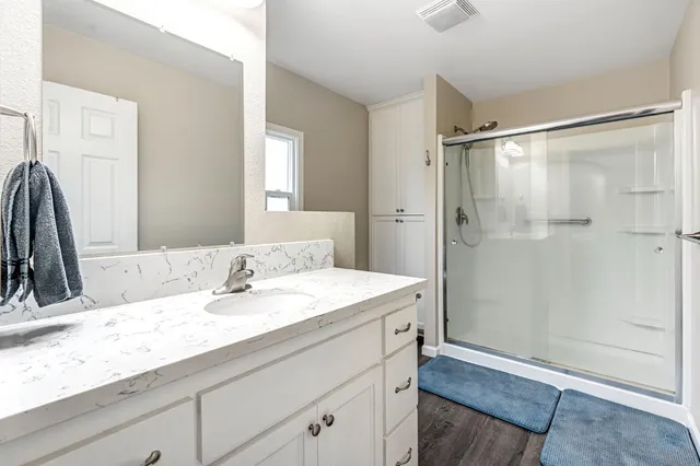 a bathroom with a granite countertop sink a mirror and a shower