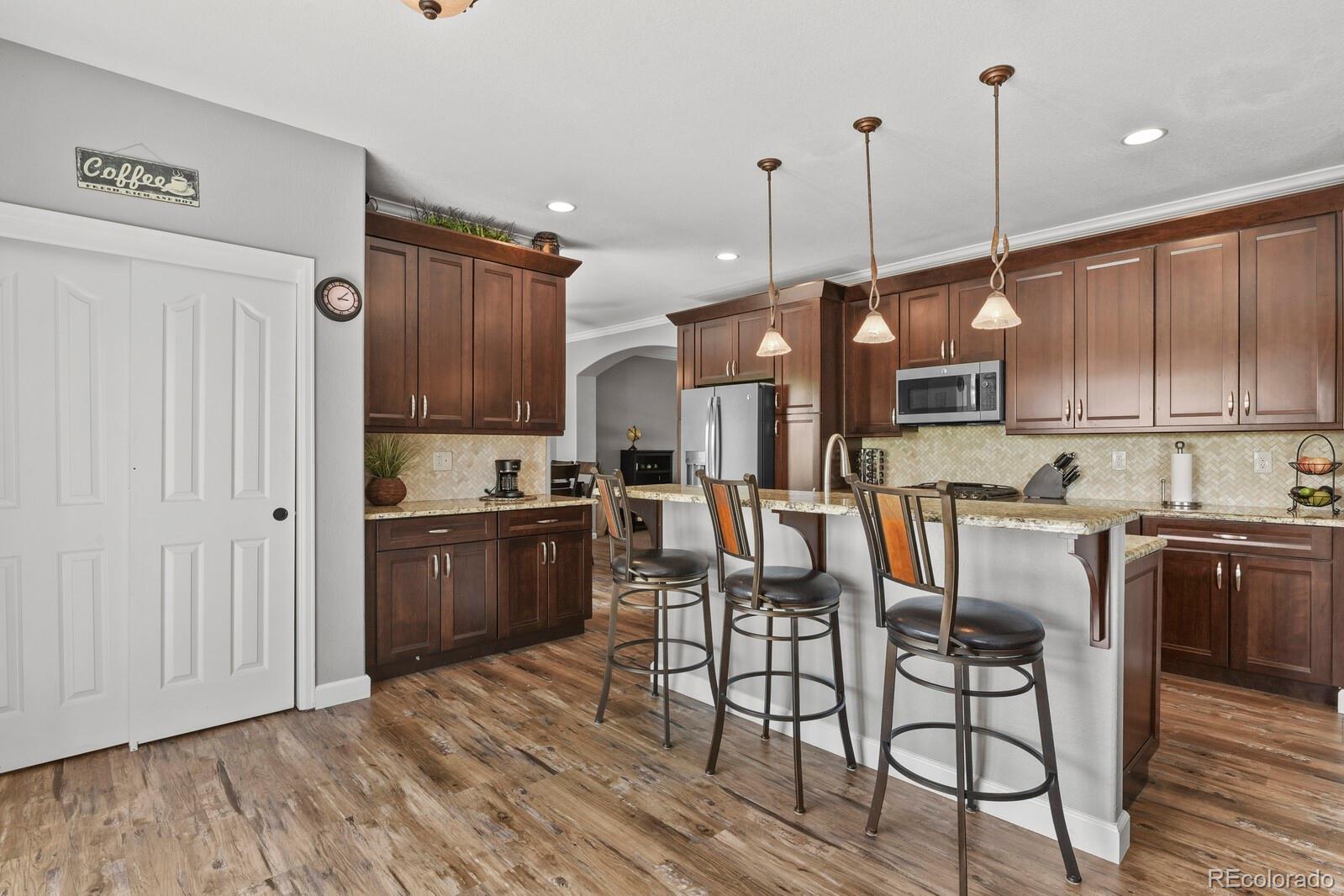 21018 Saddleback Circle Parker, CO 80138 - Photo 11 of 50 a kitchen with stainless steel appliances granite countertop a refrigerator a stove top oven a sink dishwasher and chairs with wooden floor