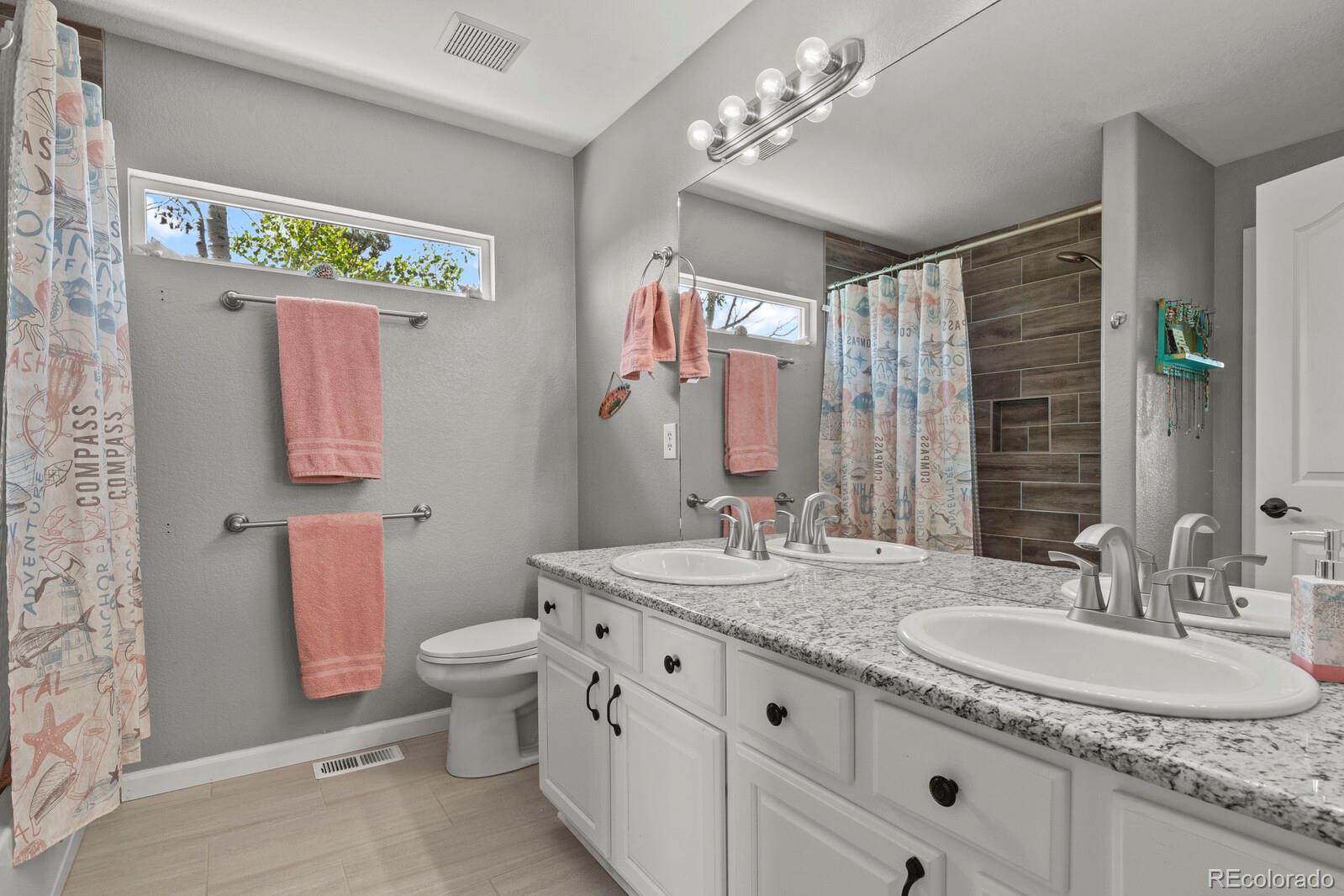 21018 Saddleback Circle Parker, CO 80138 - Photo 30 of 50 a bathroom with a granite countertop double vanity sink a mirror and a shower