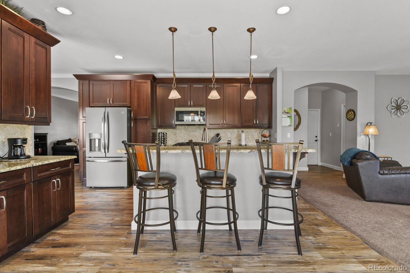 21018 Saddleback Circle Parker, CO 80138 - Photo 10 of 50 a kitchen with stainless steel appliances kitchen island granite countertop a table chairs and a refrigerator