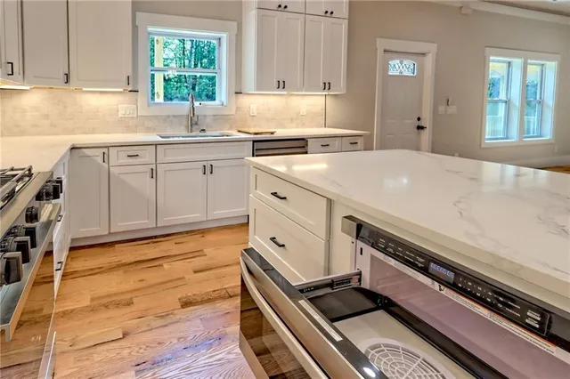 an empty room with wooden floor a ceiling fan and windows