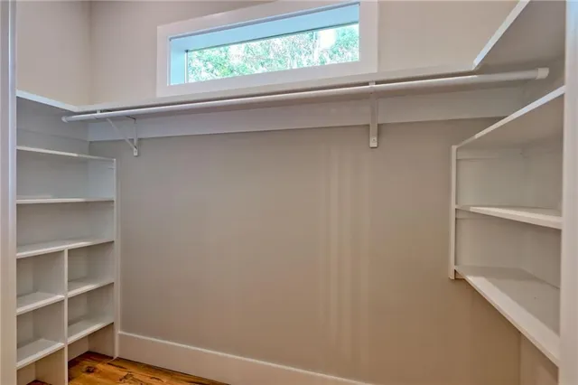 a view of an empty room with window and wooden floor