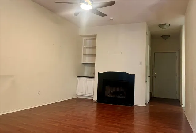 a view of an empty room with wooden floor and a fireplace