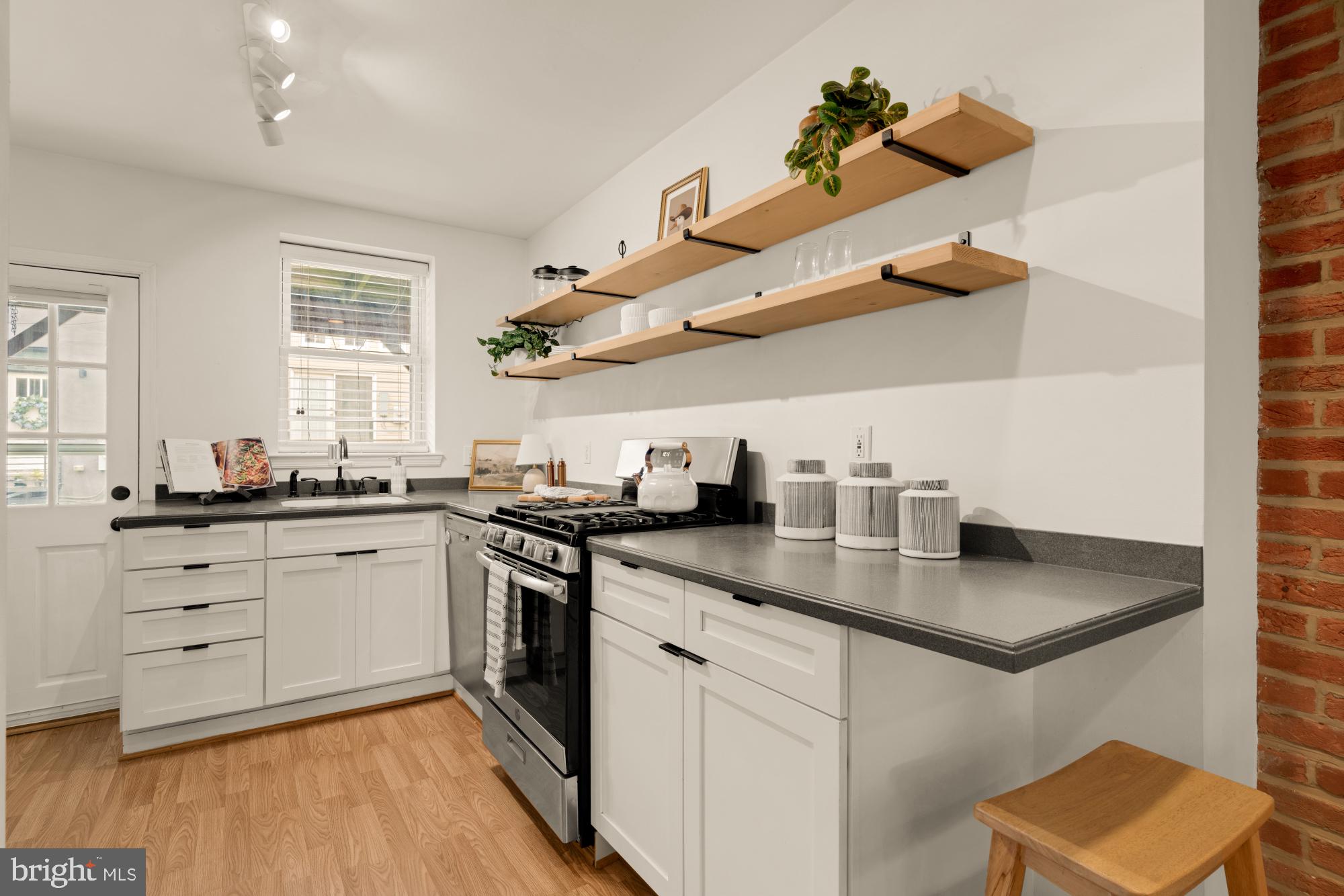 545 Gittings Street Baltimore, MD 21230 - Photo 9 of 40 a kitchen with stainless steel appliances granite countertop a sink dishwasher and white cabinets with wooden floor