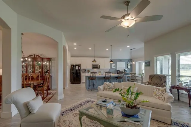 a living room with furniture kitchen view and a chandelier