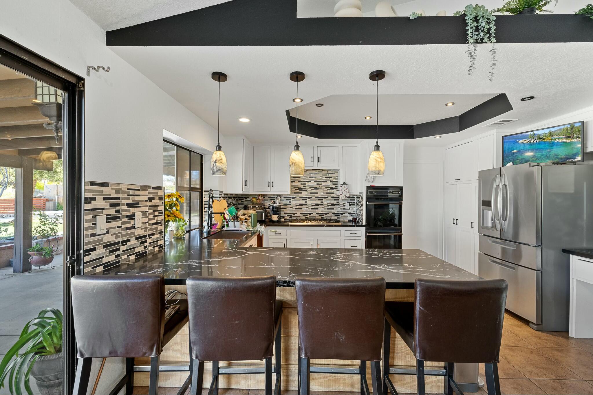 36070 43rd Street East Palmdale, CA 93552 - Photo 21 of 53 a kitchen with stainless steel appliances granite countertop a table chairs and a refrigerator