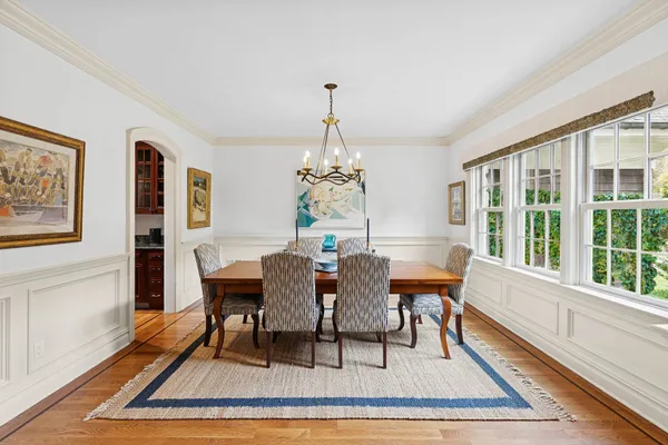 a dining room with wooden floor a chandelier a wooden table and chairs