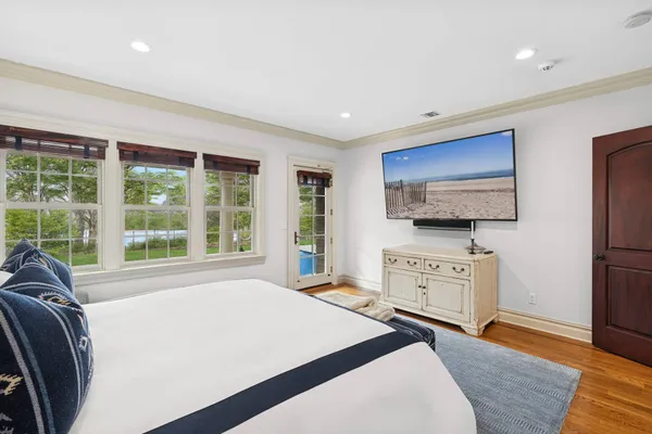 a spacious bedroom with a large bed and a flat tv screen on dresser