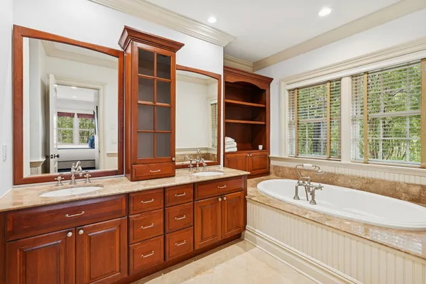 a spacious bathroom with a tub double sink window and mirror