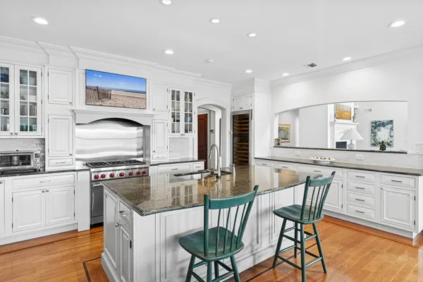 a kitchen with stainless steel appliances granite countertop a stove top oven a sink dishwasher and white cabinets with wooden floor
