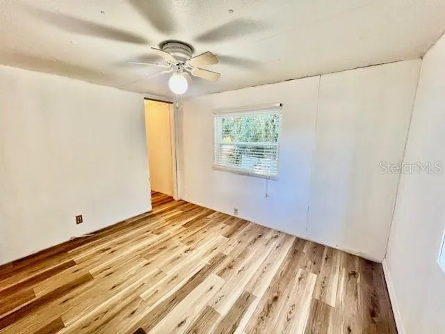 a view of a room with wooden floor and ceiling fan