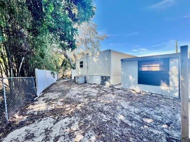 a view of a backyard with large trees and wooden fence