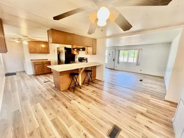 a living room with couches chairs and kitchen view with wooden floor