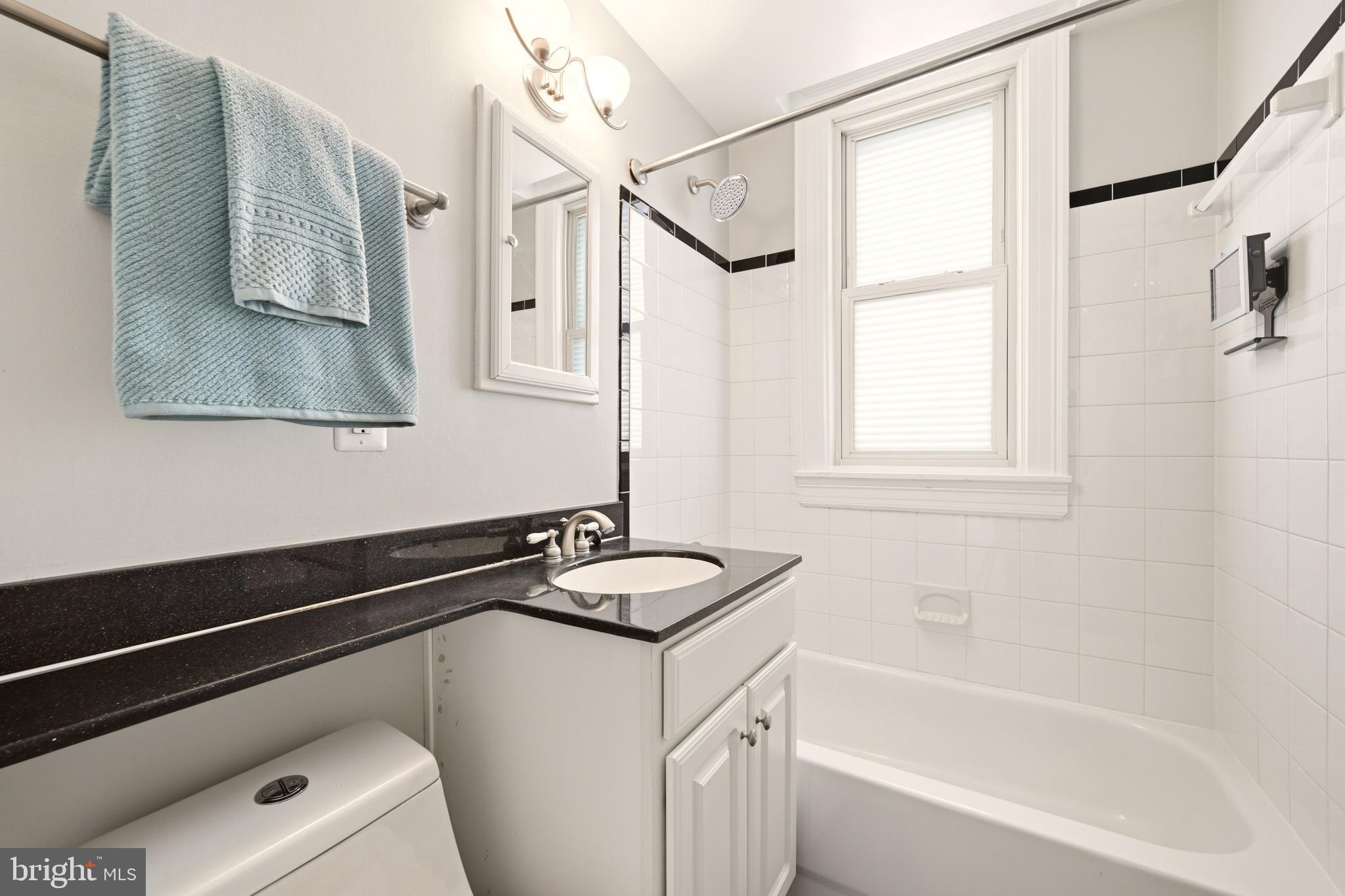 3500 13th Street Northwest, Unit 107 Washington, DC 20010 - Photo 23 of 28 a bathroom with a granite countertop sink a mirror and a bathtub