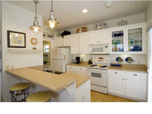 9 Blue Crab Loop Seacrest, FL 32461 - Photo 23 of 28 a kitchen with stainless steel appliances kitchen island granite countertop a sink dishwasher and white cabinets with wooden floor