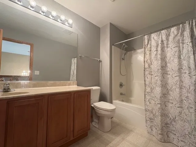 a spacious bathroom with a granite countertop sink toilet a mirror a vanity and shower