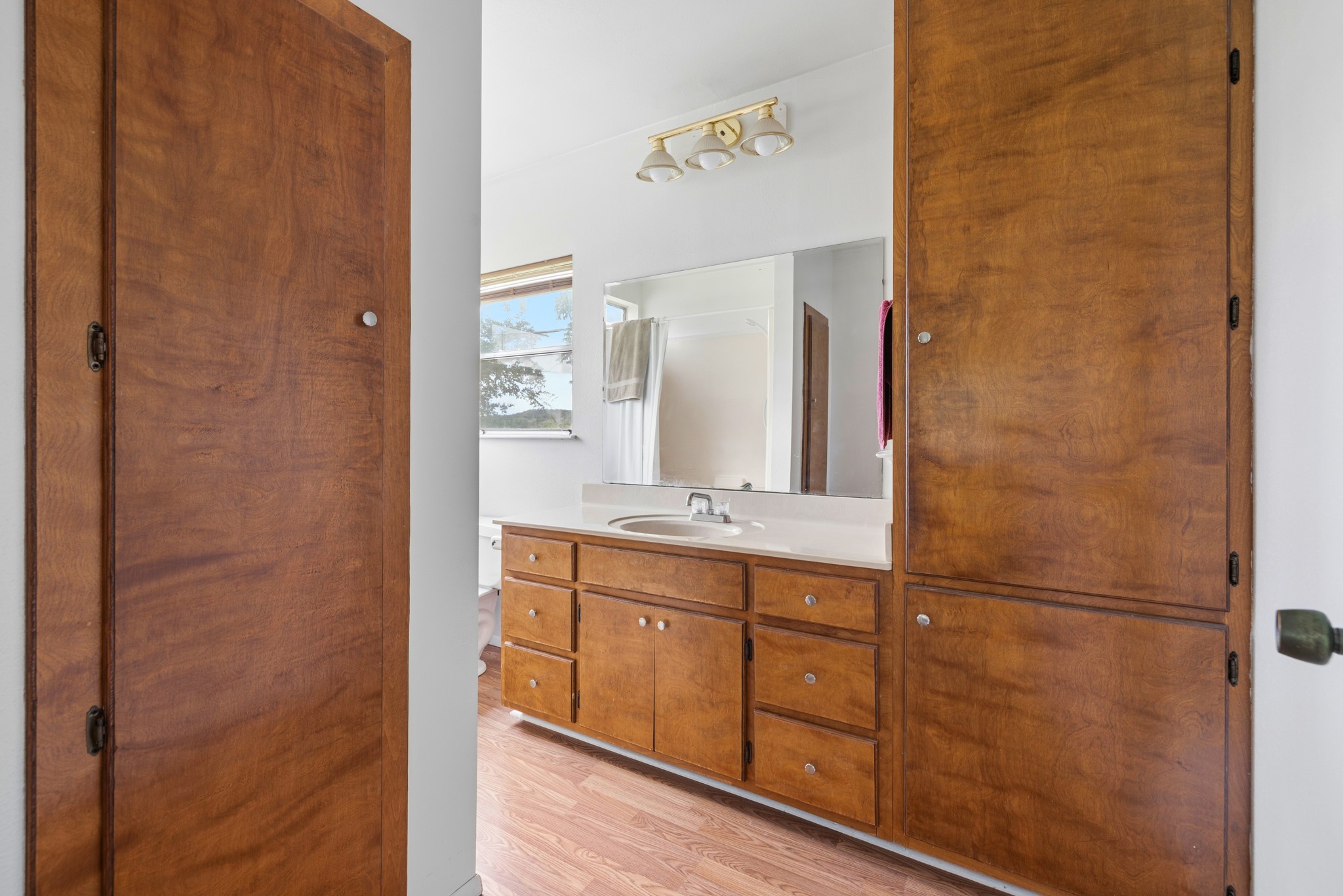 341 River View Road Fredericksburg, TX 78624 - Photo 13 of 40 Rich wood cabinetry paired with durable laminate flooring grounds this bright, functional bathroom space.