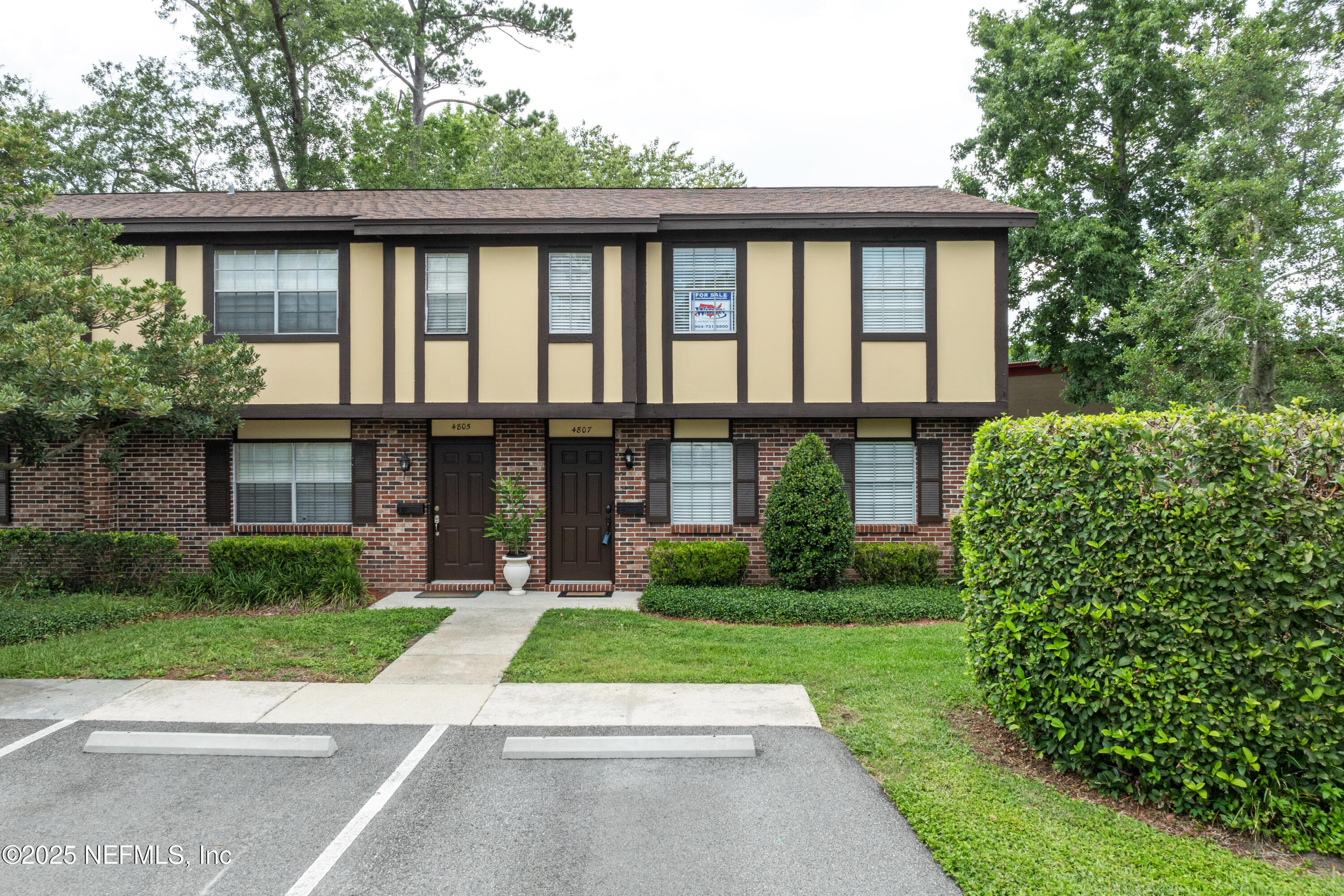 4807 Evenlode Lane Jacksonville, FL 32217 - Photo 2 of 28 a view of a brick house with a large windows and a yard with plants and large trees