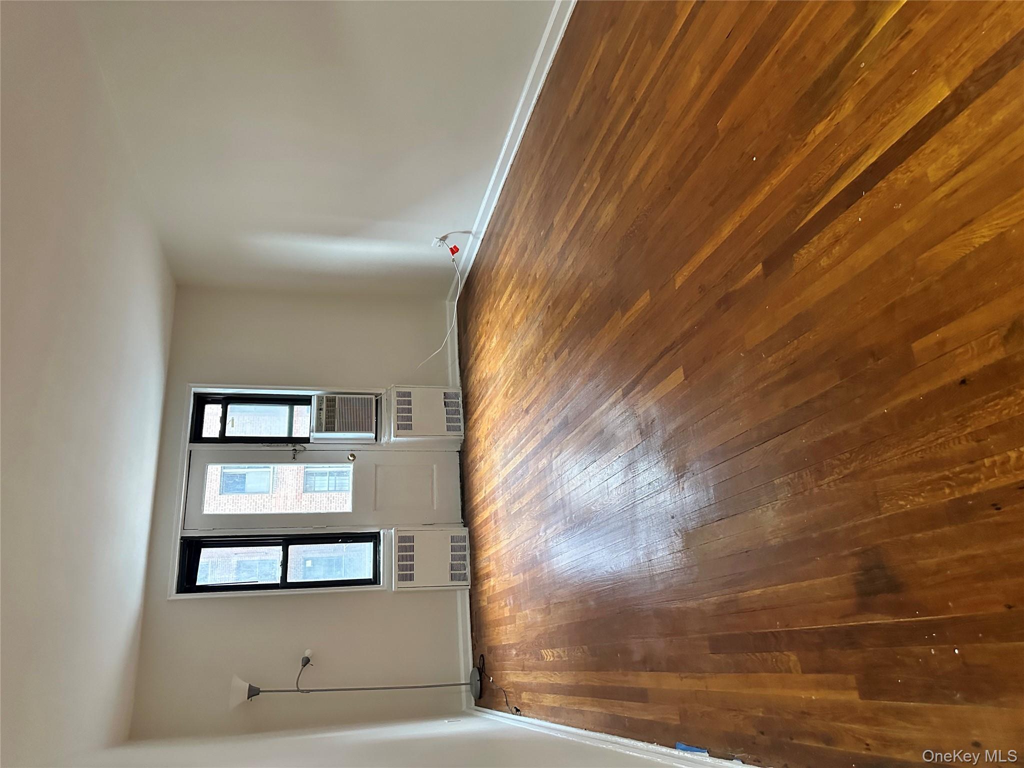 150-25 72nd Road, Unit 1J Queens, NY 11367 - Photo 12 of 14 a view of empty room with wooden floor and fan